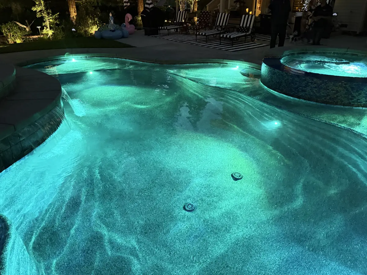 Freeform pool spa turquoise water night by Pinnacle Pools and Landscape, Sacramento CA
