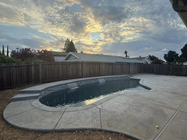 Freeform pool stamped concrete deck sunset by Pinnacle Pools and Landscape, Sacramento CA
